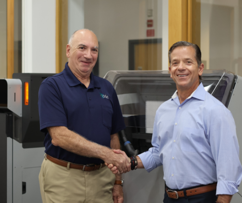 Greg Gondek (left) and Ron Angelo (right) shake hands in front of the CCAT's Formlabs fleet installed by Adia